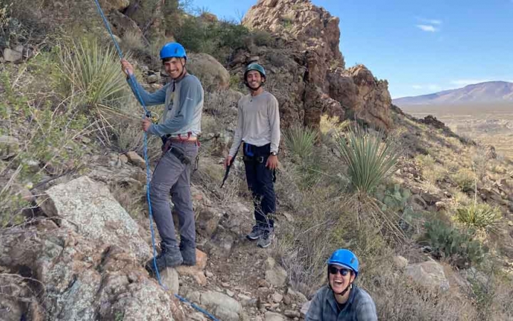 gap year students smile as they belay rock climbers on an outward bound course in big bend